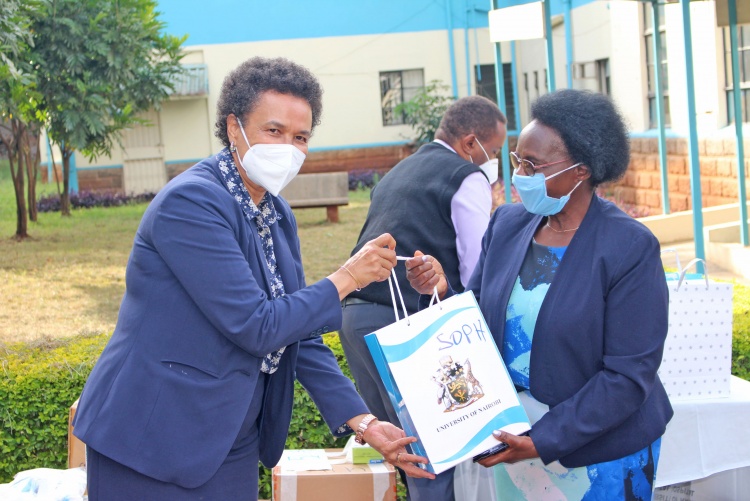 CHS Deputy Principal Prof. Evelyn Wagaiyu hands over a gift package to School of Public Health Director Prof. Joyce Olenja.