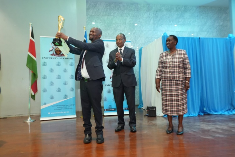 Faculty of Health Sciences Dean Prof. George Osanjo receives an award during the Staff Recognition Awards ceremony. Looking on is Chair of Council Prof. Amukoa Anangwe and acting Vice Chancellor Prof. Margaret Hutchinson.