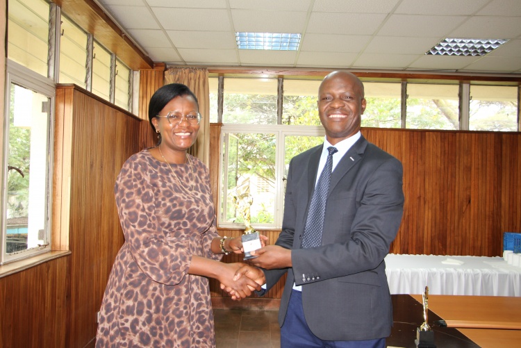 Faculty of Health Sciences Prof. Daniel Ojuka presents an award to Dr. Loise Ombanjo who emerged top in the Resource Mobilization category.